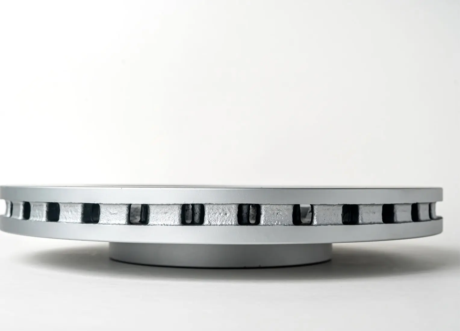 A vented brake disc viewed from the side, showcasing the cooling vents and the overall thickness of the disc.